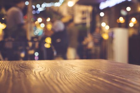 Wood table top with blur of lighting in night cafe restaurant (community) background/selective focus.の写真素材