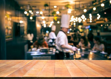 Wood table top with blur chef cooking in bar restaurant background.For create product display or design key visual layoutの写真素材