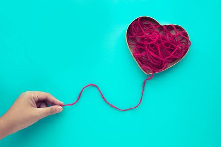 Heart shape from red yarn,rope with female hand on blue background.love,wedding,valentine concept...