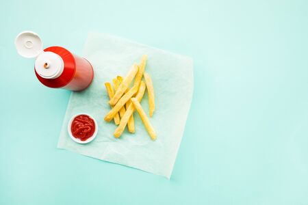 Top view of french fried with bottle of tomato sauce ( ketchup ) on color table background.Fast food...
