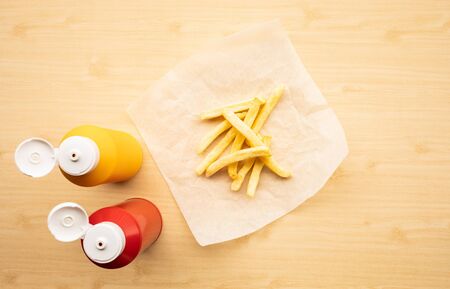Top view of french fried with bottles of tomato sauce ( ketchup ) and mustard on wood table background.Fast food and unhealthy eating concepts ideasの写真素材