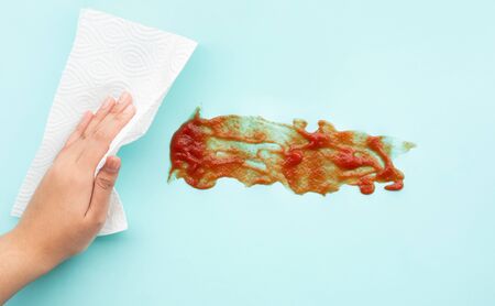 Female hand cleaning (ketchup) tomato sauce stai with tissue paper.close upの写真素材