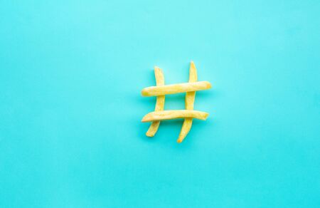 Hashtag sign icon with french fried on blue color background.Food, nutrition and social conversation concepts ideasの写真素材