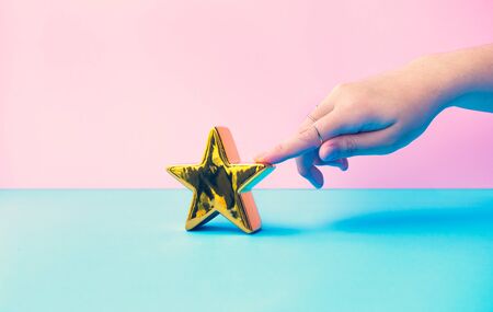 Customer review concepts with female finger and gold star on pastel color background.feedback...