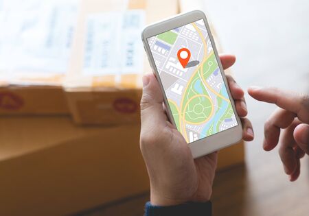 Delivery and online shopping concepts with young person using digital map with smartphone on product package box.Ecommerce market.Transportation logistic.Business retail.の写真素材