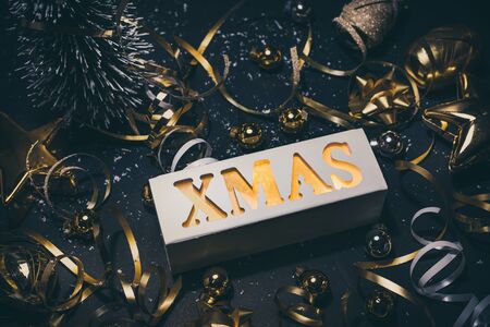 Merry christmas,xmas and celebration concepts with xmas lightbox text and ornament in golden color on dark background.winter season and anniversary dayの写真素材