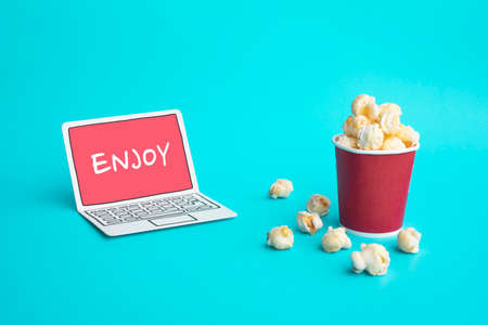 Enjoy with vdo entertainment or movie concepts with text on paper art laptop and pop corn on color...