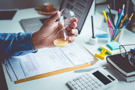 Time and motivation concepts with person hand holding hourglass on desk table.vision or inspiration for lifeの写真素材