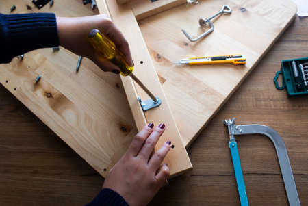 Woman assembly wooden furniture,fixing or repairing house with screwdriver tool.modern living...