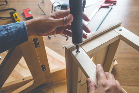 Man assembly wooden furniture,fixing or repairing house with screwdriver tool.modern living concepts ideasの写真素材