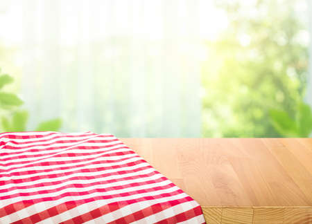 Red fabric,cloth on wood table top on blur window in morning background.For montage product display or design key visual layout.の写真素材