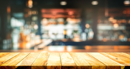 Empty the top of wooden table with blurred cocktail counter bar and wine bottles wide background.の写真素材