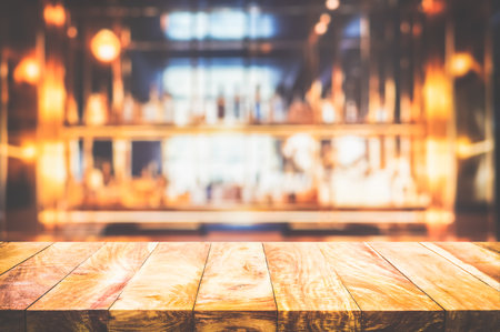 Empty the top of wooden table with blurred cocktail counter bar and wine bottles wide background.の写真素材