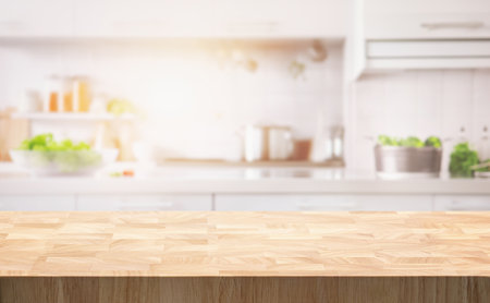 Selective focus.End grain wood counter table top on blur white cozy kitchen in morning background.For montage product display or design key visualの写真素材