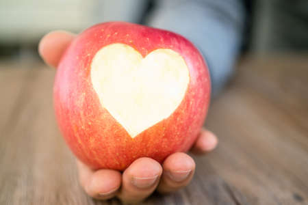 hand holding apple with heart cut, giving you the fresh heart apple.の写真素材