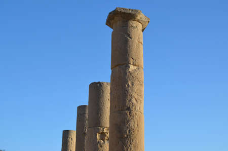 Four ancient column tops set against a bright blue skyの写真素材