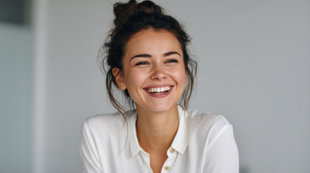 A joyful young woman is smiling brightly, radiating happiness and positivity in a contemporary indoor space. Her natural beauty and relaxed demeanor embody serenity and confidence.の素材