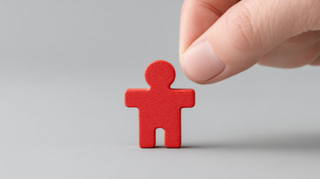 A human hand reaches for a small red figure, representing support and guidance in personal and professional contexts. Perfect for themes of leadership and growth.の素材