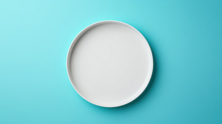 This image features a simple white ceramic plate on a vibrant turquoise background, perfect for showcasing culinary creations or enhancing food photography.の素材