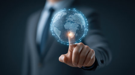 A businessman uses his finger to touch a virtual globe, symbolizing the connection and innovation in the global business landscape and modern technology.の素材