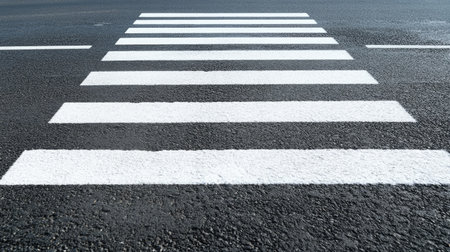 Freshly painted white zebra crosswalk markings on smooth asphalt, symbolizing urban safety and modern road infrastructure.の素材