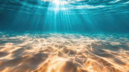 Underwater view of the seabed with golden sand, bathed in sunlight filtering through the crystal blue ocean, creating gentle ripples.の素材