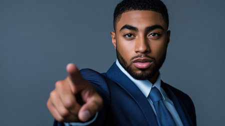 A confident business leader in a sharp blue suit, finger pointing towards the camera, perfect for professional coaching and leadership visuals.の素材