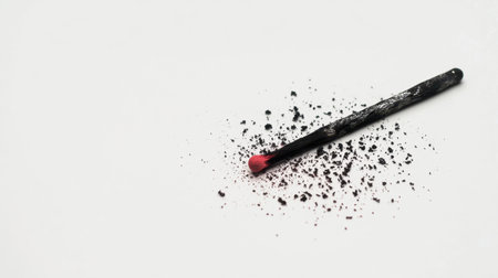 A single burnt matchstick with its tip glowing faint red, scattered ashes on a clean white background, symbolizing emotional burnout and exhaustion.の素材