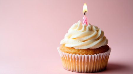 Simple cupcake with a lit candle, placed on a solid pale pink background, capturing the essence of a quiet birthday celebration.の素材