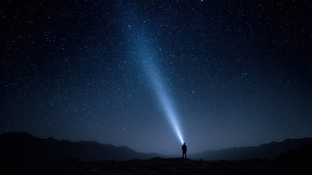 A lone person stands in a serene landscape, using a flashlight to illuminate the dark night sky filled with stars, showcasing the beauty and mystery of our universe.の素材