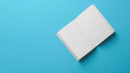 Mockup of a blank white book on a solid blue background, perfect for showcasing custom cover designsの素材