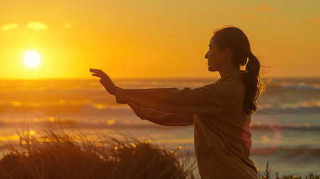A woman practicing tai chi on a beach at sunrise, embodying mental and physical wellnessの素材