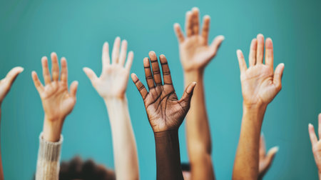 Symbol of equality: close-up of diverse hands raised in celebration and unity.の素材
