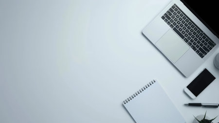 A sleek office desk with a laptop, notepad, and pen, with ample white space for adding text or a logoの素材