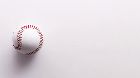 A baseball resting on a clean, uncluttered background with space for copy, creating a simple sports banner.の素材