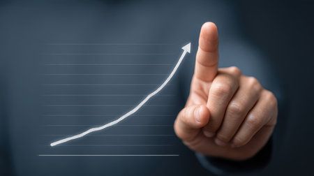 A close-up of a hand touching an upward graph, symbolizing business growth and success. Ideal for illustrating concepts of progress, motivation, and achievement.の素材