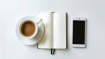 Flat lay of an open notebook with a smartphone and coffee cup, on a white tableの素材