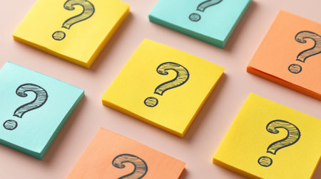A vibrant arrangement of hand-drawn question marks on sticky notes in various colors displays creativity and curiosity, perfect for showcasing brainstorming and organization in office settings.の素材