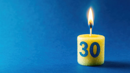 A vibrant yellow candle featuring the number 30 stands against a blue background. The warm flame signifies celebration and joy, perfect for anniversaries.の素材