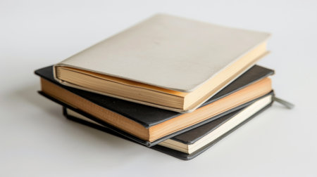 A stack of blank notebooks awaiting inspiration, set against a clean white backdrop.の素材