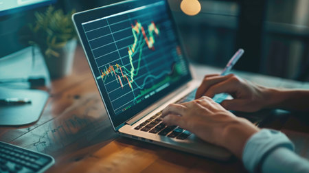 Businessperson reviewing financial charts on a laptop, focused and determinedの素材