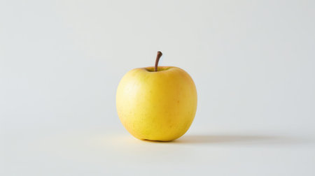 A yellow apple with a smooth, unblemished skin, standing alone on a white background, highlighting its simplicity and natural beautyの素材