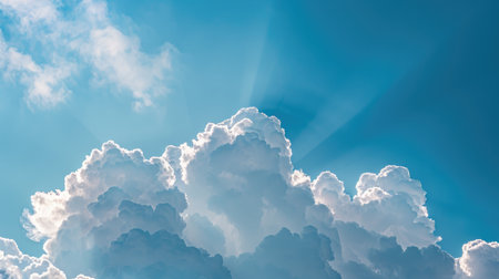 Puffy, white clouds floating in a bright blue sky, with the sun shining through and casting a beautiful lightの素材