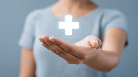 A person extends an open hand with a glowing health symbol above, symbolizing care, support, and a modern approach to healthcare and wellness concepts.の素材