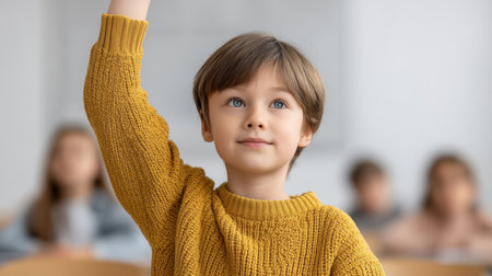 A young boy in a cozy yellow sweater raises his hand in a classroom, showcasing eagerness to learn and interact, surrounded by fellow students engaged in study.の素材