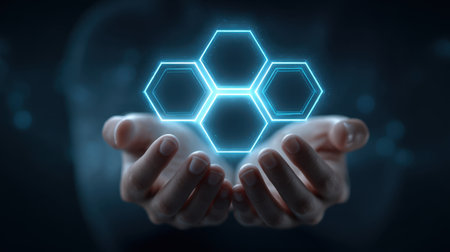 A pair of hands cradles illuminated hexagonal shapes, representing technology and innovation against a dark background, ideal for concepts of digital connectivity.の素材