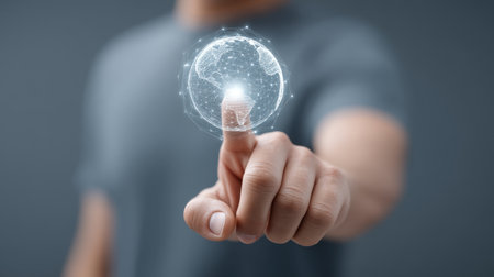 A human hand elegantly interacts with a holographic digital globe, emphasizing the fusion of technology and innovation in modern design.の素材