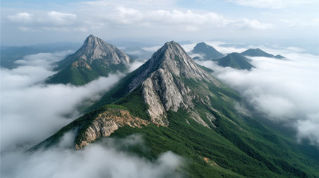 Discover a stunning mountain landscape featuring majestic peaks and clouds gracefully rolling over the lush environment. An aerial view capturing nature's beauty and tranquility.の素材