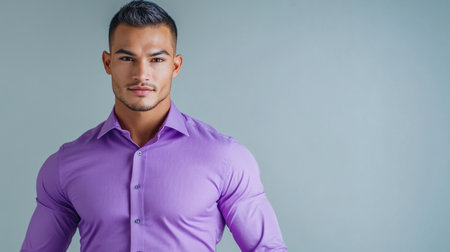 A poised Hispanic man in a purple shirt stands confidently against a plain backdrop, conveying style and professionalism for marketing purposes.の素材