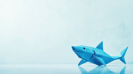 A vibrant blue origami shark stands on a minimalist surface, showcasing creativity and craftsmanship. Ideal for educational and artistic projects.の素材